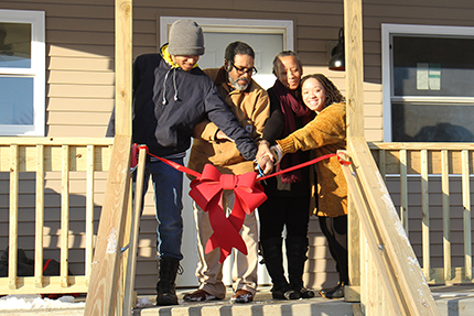 Calvin and Andrea Boyd (center) and their children Noah (left) and Teya (right) cut the ribbon on their new Ypsilanti Township home on Sunday, Jan. 20. | Photo by Rich Rezler