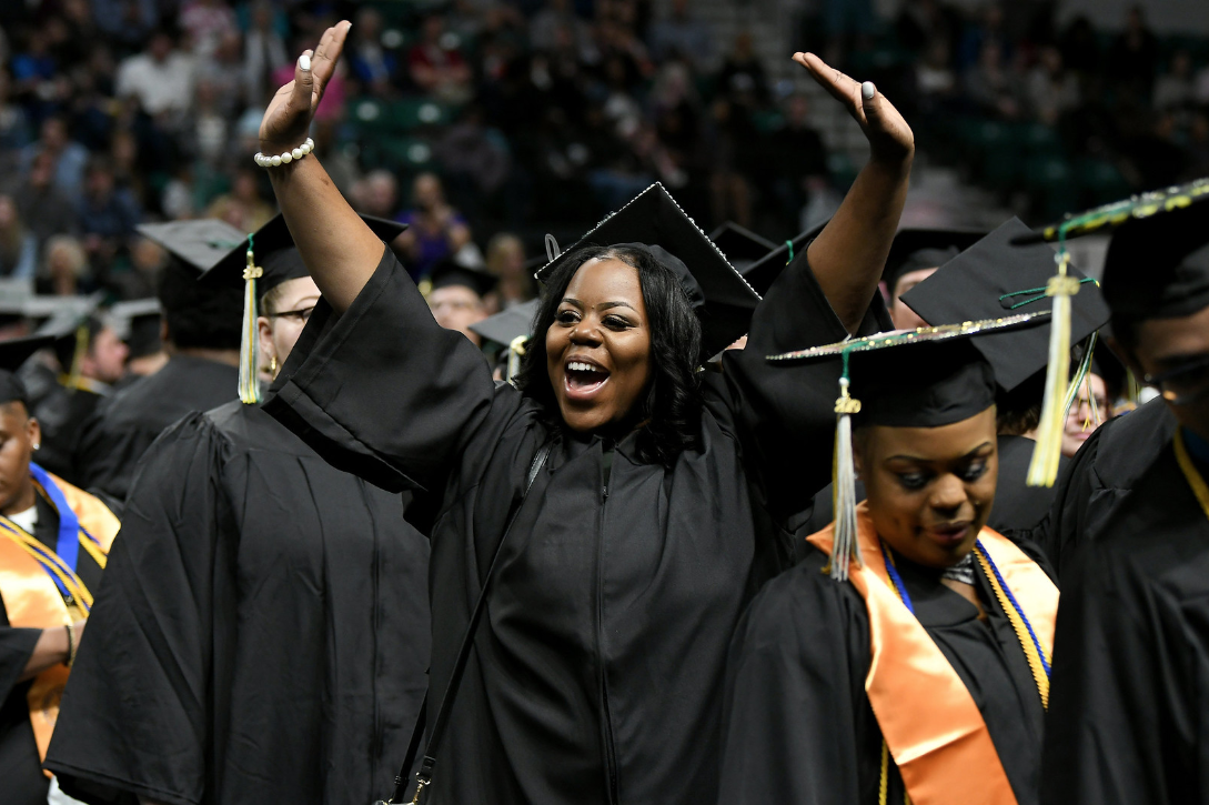 WCC graduate Tanisha Harper of Detroit waves to family in the crowd prior to the commencement ceremony on May 18. (Photo by Lon Horwedel)